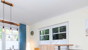 Une cuisine moderne avec un plan de travail en bois, un coin repas avec des chaises à revêtement gris et une fenêtre agrémentée de rideaux bleus.