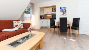 Un salon moderne comprenant un canapé, une table basse et un coin repas avec des chaises et une table.