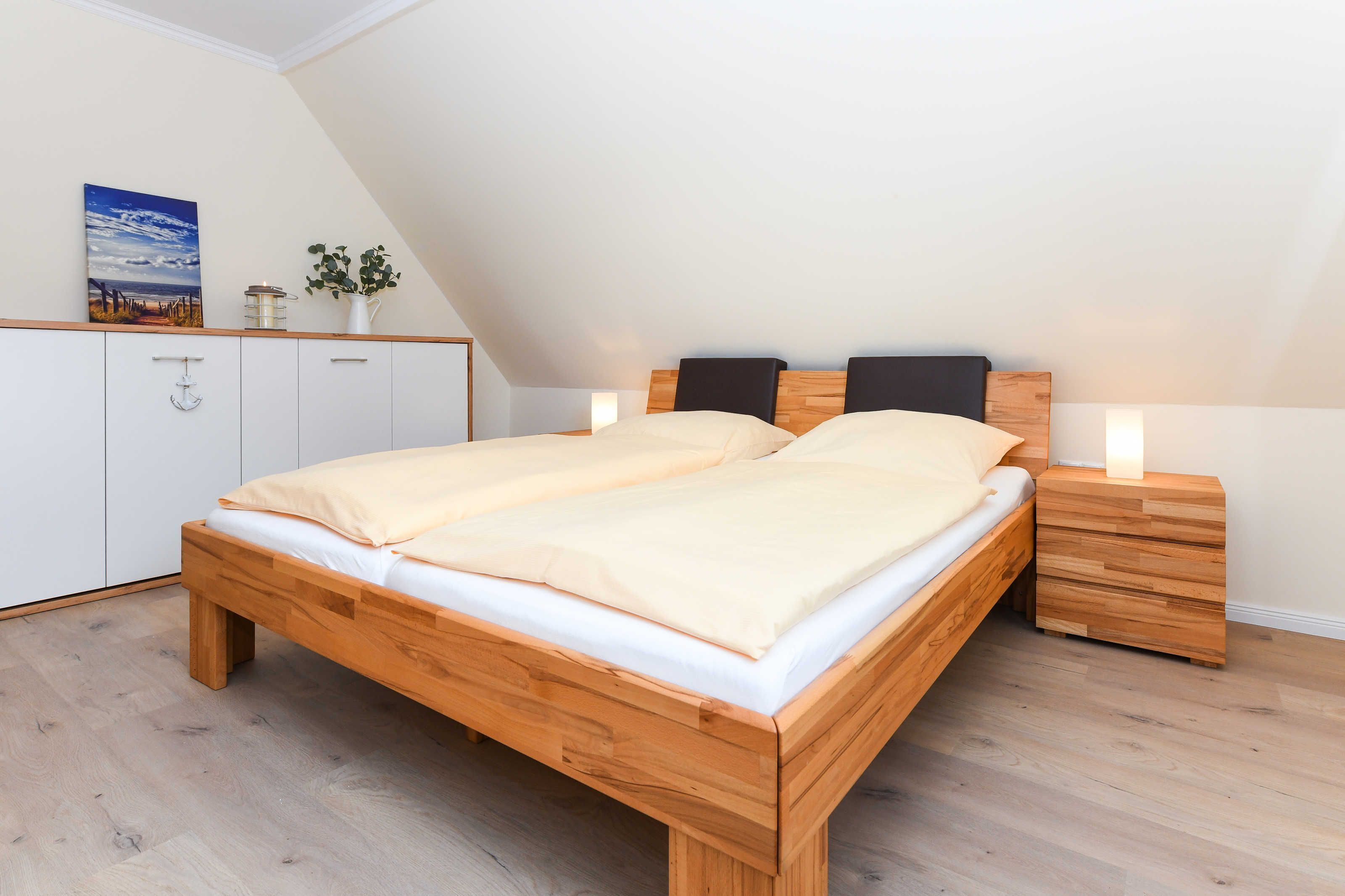 A bedroom with a wooden bed, white cabinets, and a small bedside table with a lamp.