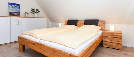 A bedroom with a wooden bed, white cabinets, and a small bedside table with a lamp.