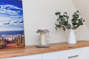 A wooden shelf with a candle holder, a potted plant, and a framed picture of a beach scene. - Sonnendeck Vacation Apartment - Meerzeit House (Esens)