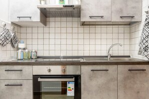 A modern kitchen with a built-in oven, a stainless steel sink, and a tiled backsplash.