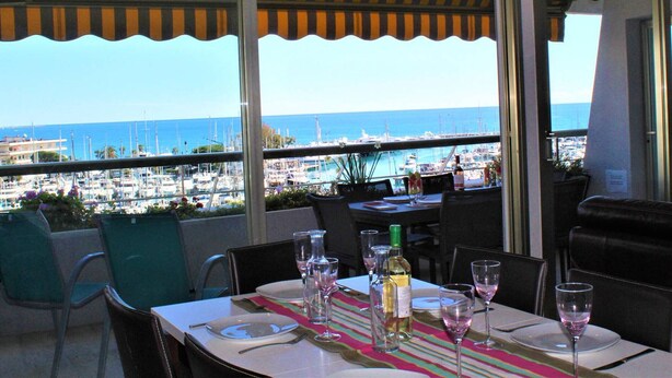 A dining area with a table set for two, overlooking a marina with boats.