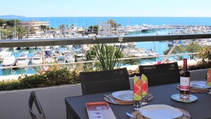 A dining table set for two with a view of a marina and boats.
