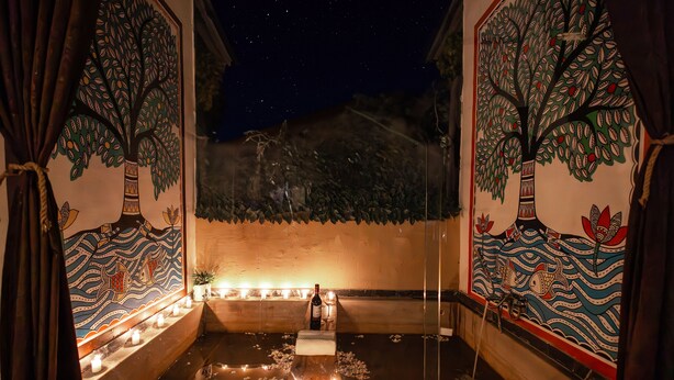 A room with a wooden bench, candles, and a bottle of wine. - Panarpani Retreat Pachmarhi (Pipariya)