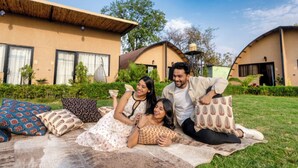 A group of people relaxing on a blanket in a courtyard with a house in the background. - Panarpani Retreat Pachmarhi (Pipariya)
