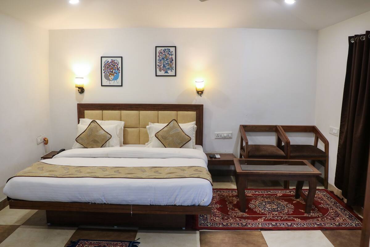 Une chambre d’hôtel bien aménagée, avec un grand lit, deux lampes fixées au mur, une petite table et une chaise.