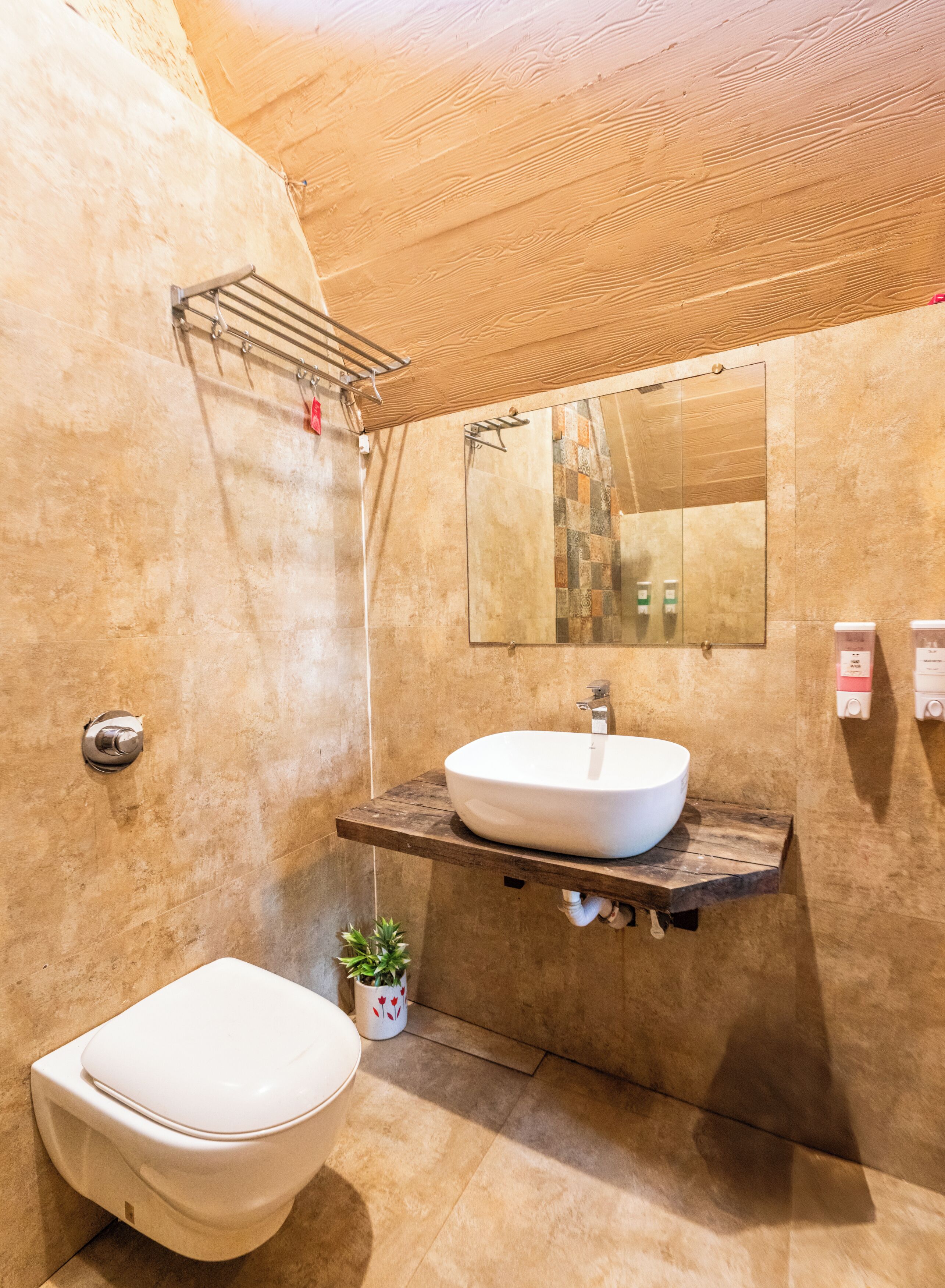 Een moderne badkamer met een houten wastafel, een grote spiegel, een toilet en een kleine plant in pot.