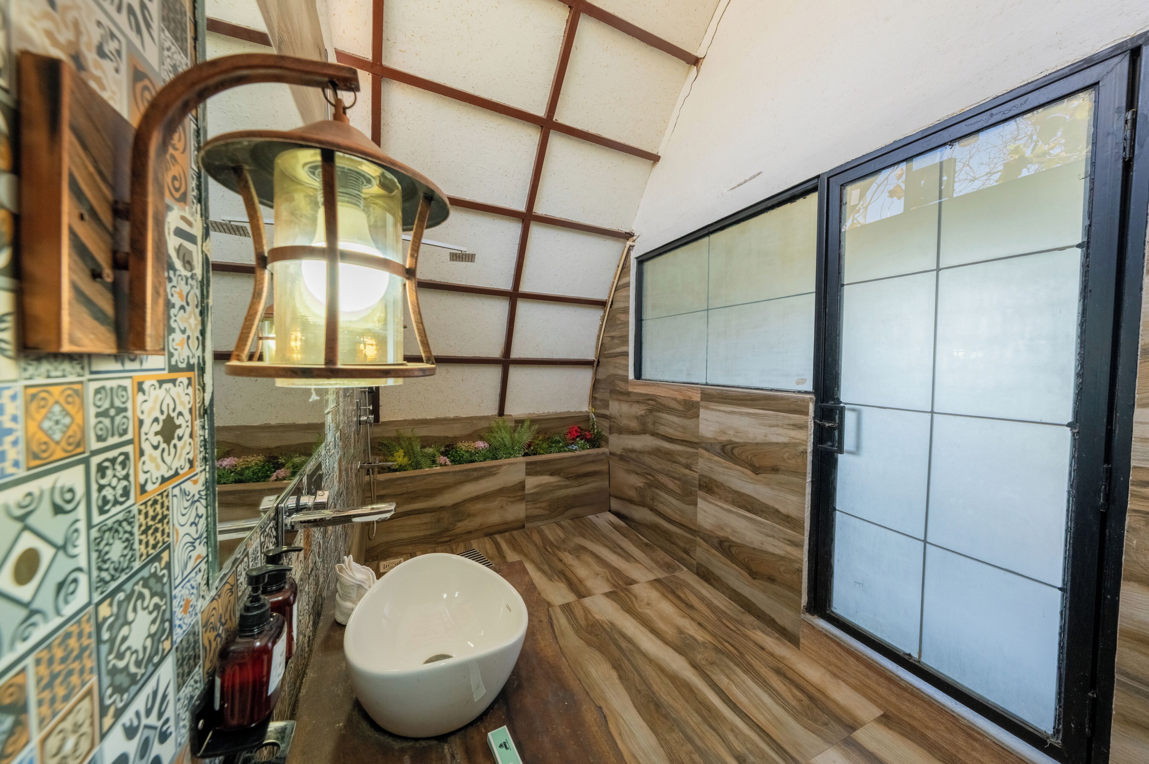 A bathroom with a large window, a sink, and a decorative wall with patterned tiles.