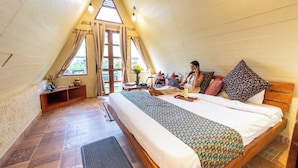 A cozy, triangular-roofed bedroom with a bed, a desk, and a laptop. - Panarpani Retreat Pachmarhi (Pipariya)