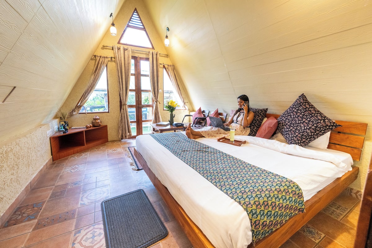 Une chambre confortable, avec un toit en forme de triangle, comprenant un lit, un bureau et un ordinateur portable.