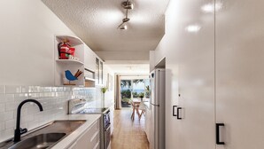 A modern kitchen with white cabinets, a stainless steel sink, and a view to the outside. - THE GRASSY KNOLL Panoramic Beach Apartment  - Sunrise Beach (Sunrise Beach)