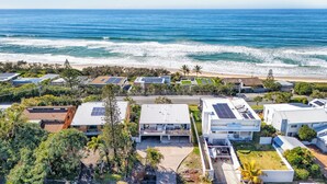 A coastal residential area with modern houses featuring solar panels, a beach, and lush greenery. - THE GRASSY KNOLL Panoramic Beach Apartment  - Sunrise Beach (Sunrise Beach)