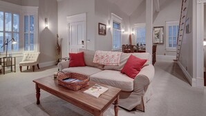 Ein geräumiges Wohnzimmer mit einem großen, beige gefärbten Sofa, einem Holztisch und einem weißen Sessel.