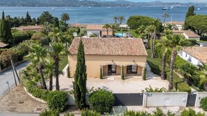 A Mediterranean-style villa with a tiled roof, surrounded by palm trees and a view of the sea with boats. - Villa at the entrance to St Tropez sea view beach 2 minutes walk (Gassin)