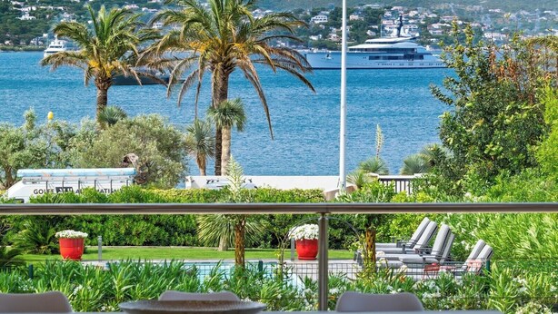 A terrace with a view of the sea, palm trees, and a yacht. - Villa at the entrance to St Tropez sea view beach 2 minutes walk (Gassin)