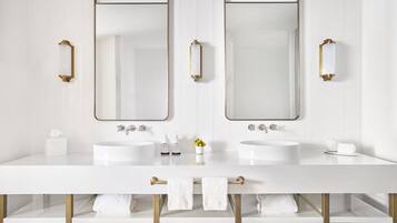 Ein modernes Badezimmer mit zwei Waschbecken, großen Spiegeln und goldenen Armaturen.