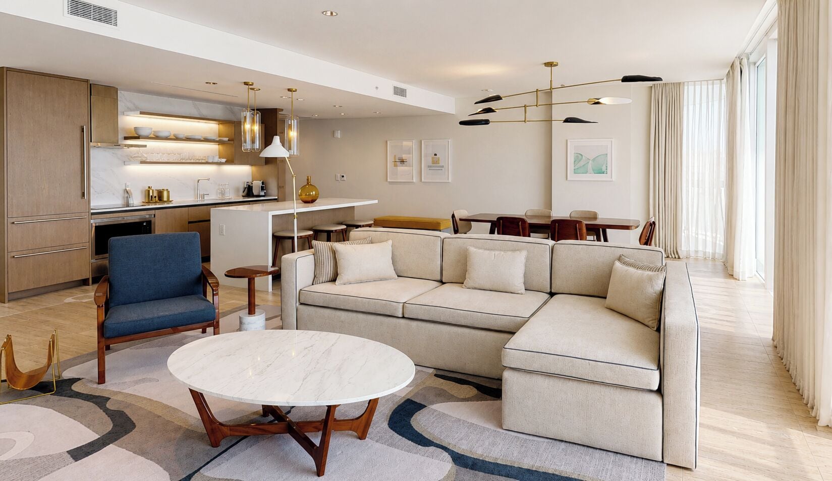 A modern living room with a sofa, a round table, and a blue armchair.