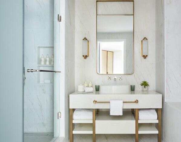 A modern bathroom with a white marble sink, gold fixtures, and a glass shower enclosure. - Four Seasons Hotel and Residences Fort Lauderdale (Fort Lauderdale)