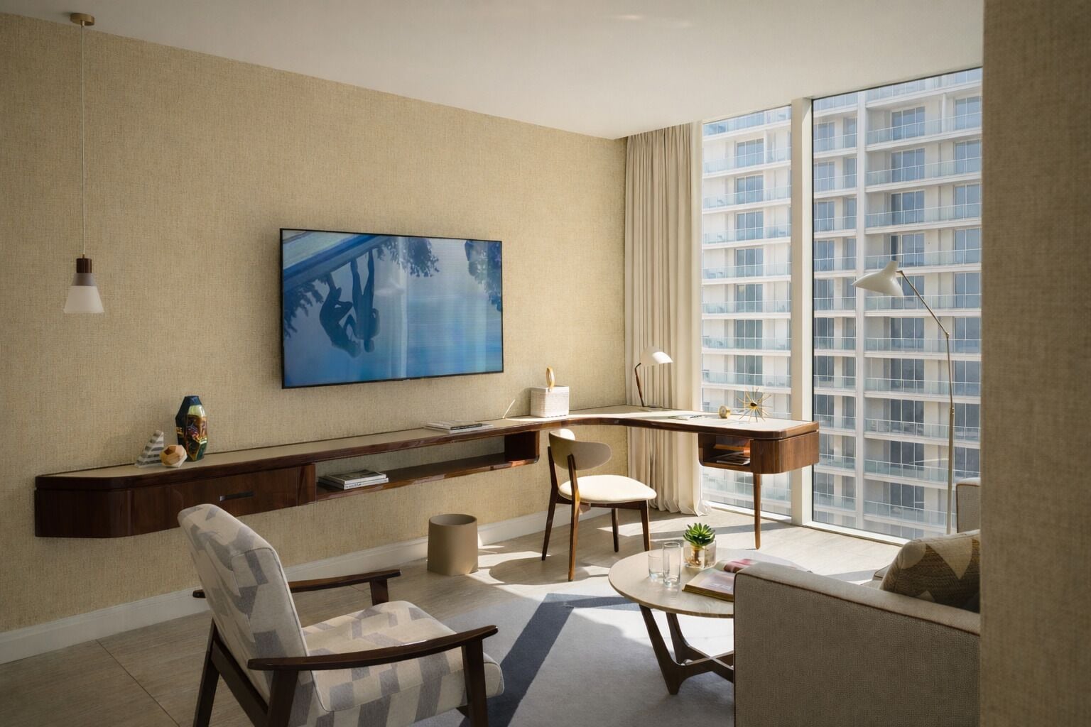 A modern living room with a large TV, a desk, and a comfortable seating area.