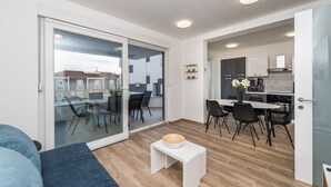 A modern apartment with a dining area, kitchen, and a balcony with a view of the neighborhood. - Pool Apartments Banta B (Novalja)