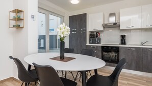 A modern kitchen with white cabinets, a built-in oven, and a coffee maker. - Pool Apartments Banta B (Novalja)