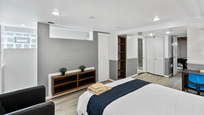 Ein modernes Hotelzimmer mit Bett, Schreibtisch, Kleiderschrank und einer Sitzecke.