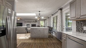 Una cocina moderna con una isla central, electrodomésticos de acero inoxidable y un comedor con vistas.