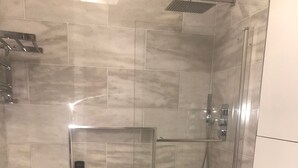 Un bagno moderno con doccia vetro, vasca da bagno separata e un water.