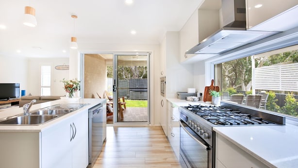 A modern kitchen with a central island, stainless steel appliances, and a view of the backyard.