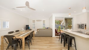 A modern kitchen with a white countertop, a built-in oven, and a dining area with a wooden table and chairs.
