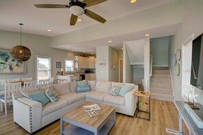 A spacious living area with a white sectional sofa, a wooden coffee table, and a ceiling fan.