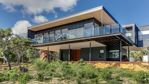 A modern two-story house with a flat roof, large glass windows, and a balcony. - Carpe Artes – Peaceful Creative Luxury with Ocean Views (Margaret River)