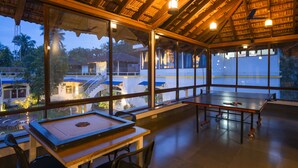 Un espacio interior amplio con mesa de ping pong, ventanas grandes y vistas al exterior.