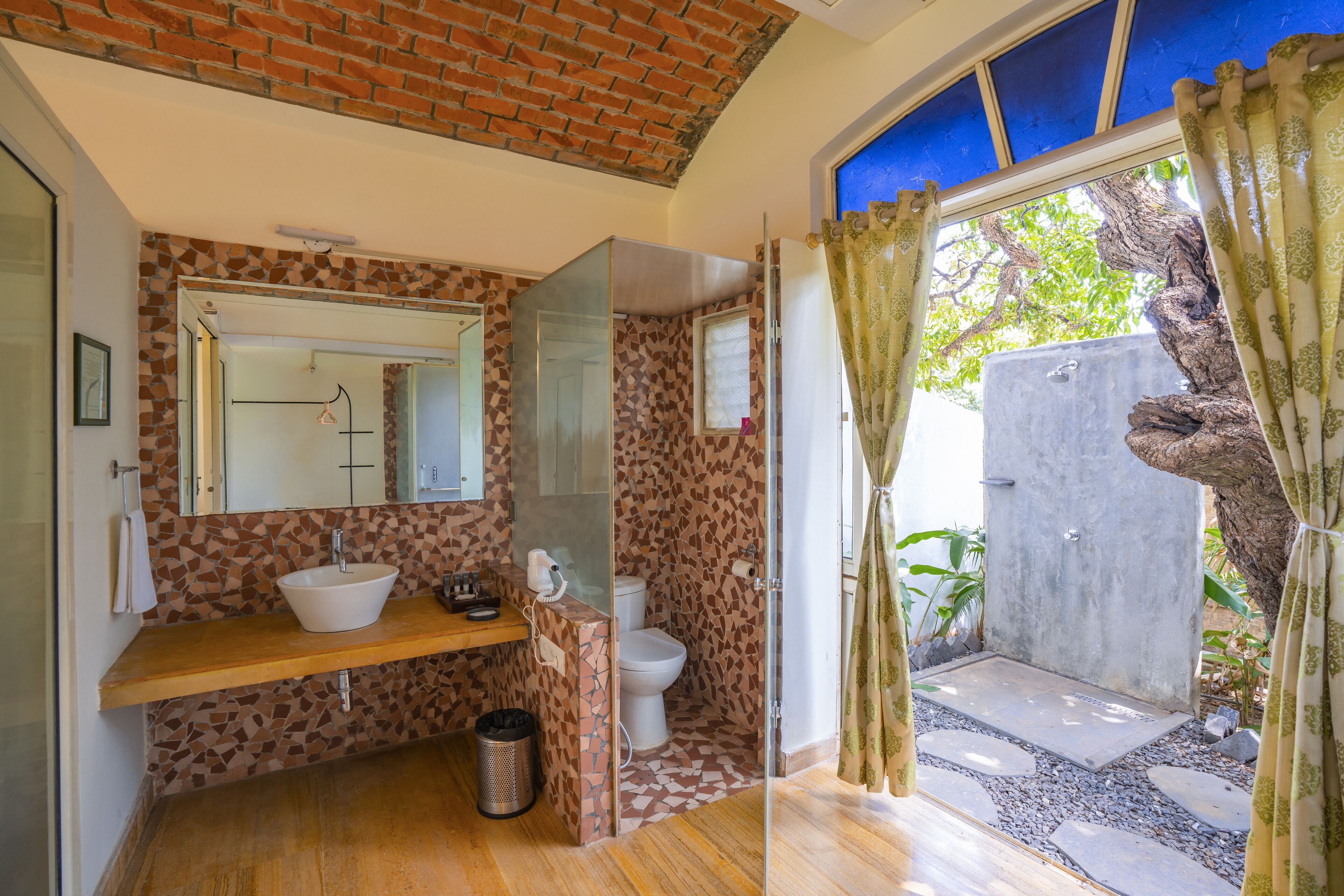 A bathroom with a tiled backsplash, a wooden vanity, a white sink, a toilet, and a shower area with a glass door.