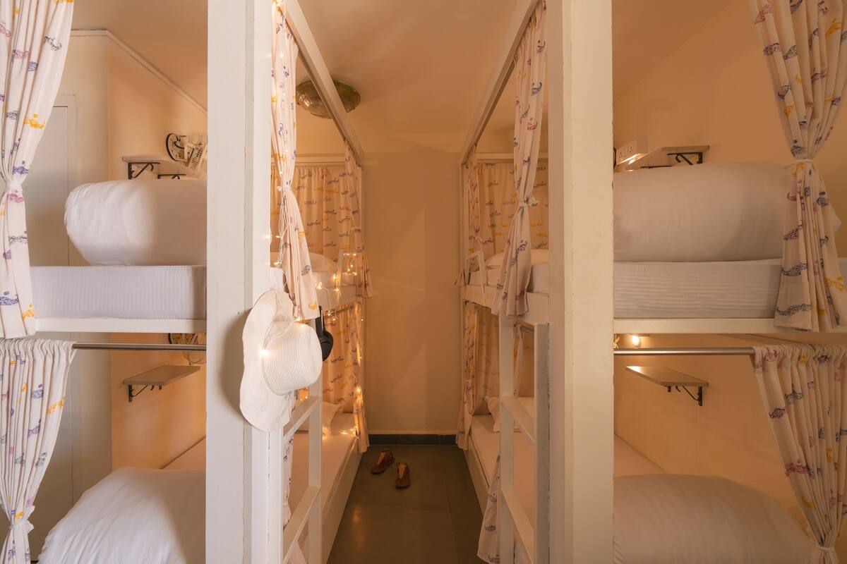A narrow hallway with bunk beds on either side, each with a small shelf and a hanging hat.