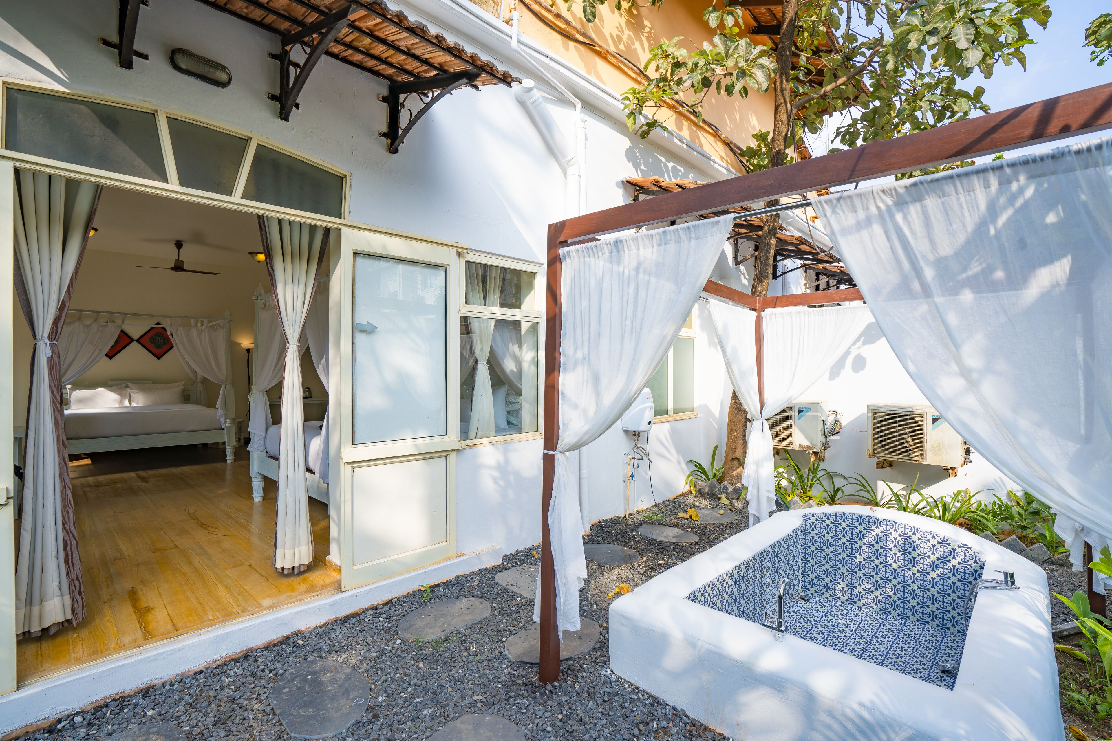 A bedroom with a bed, a window, and a small balcony area with a white canopy.
