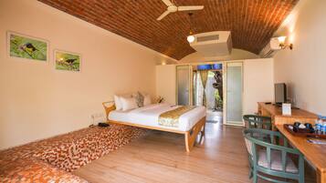 Un dormitorio con cama, escritorio, sillas, ventilador de techo y techo de ladrillo.