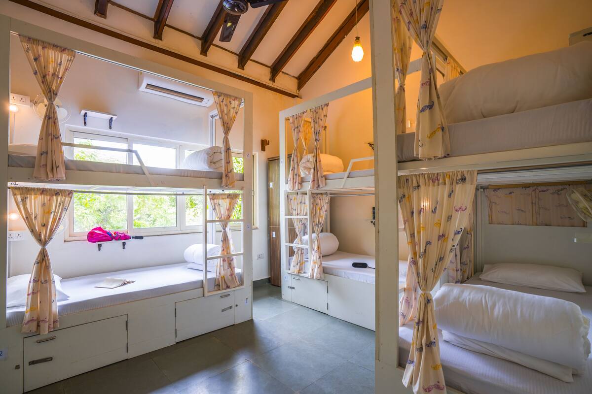 A room with bunk beds, curtains, a window, and a fan.