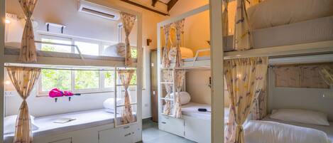 A room with bunk beds, curtains, a window, and a fan.