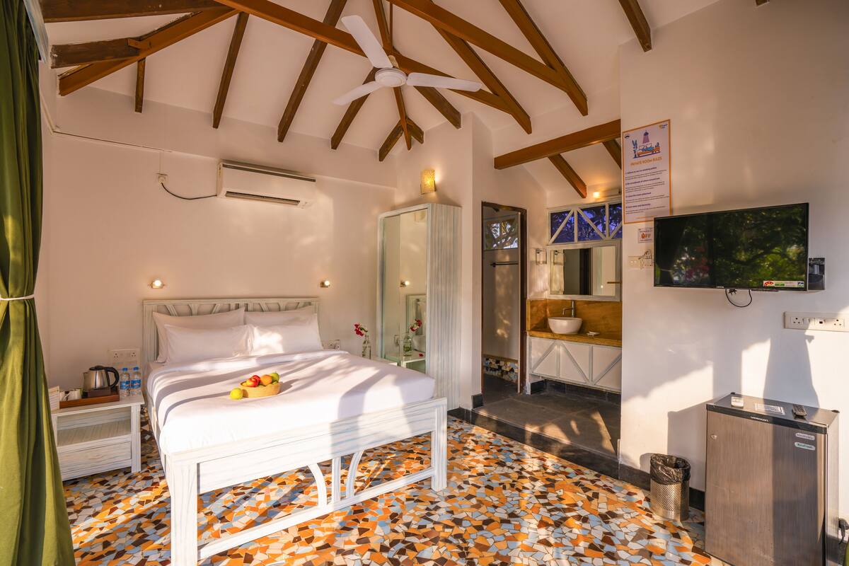 A bedroom with a bed, a TV, a mirror, and a bathroom.