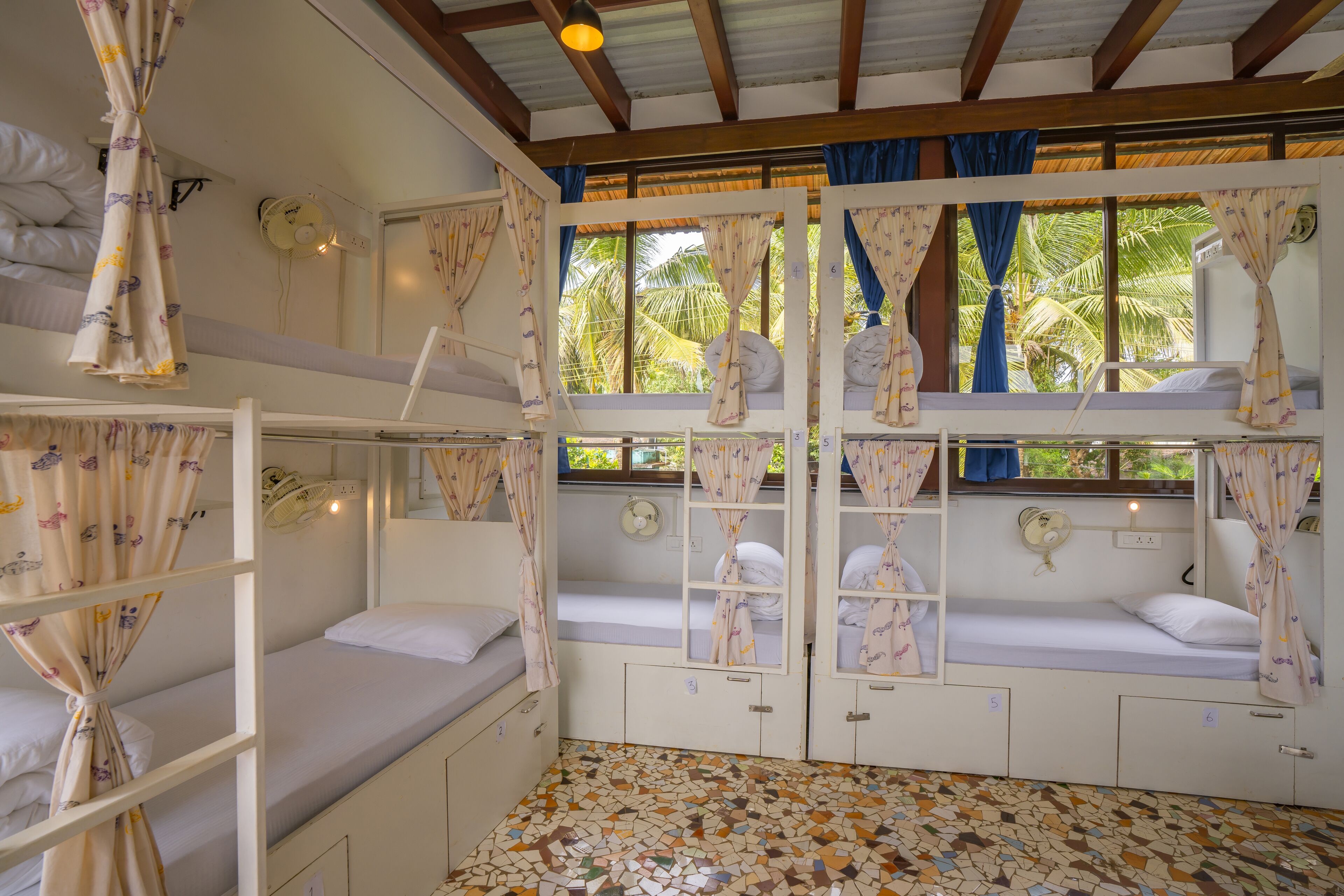 A room with bunk beds, a tiled floor, and a window with curtains.