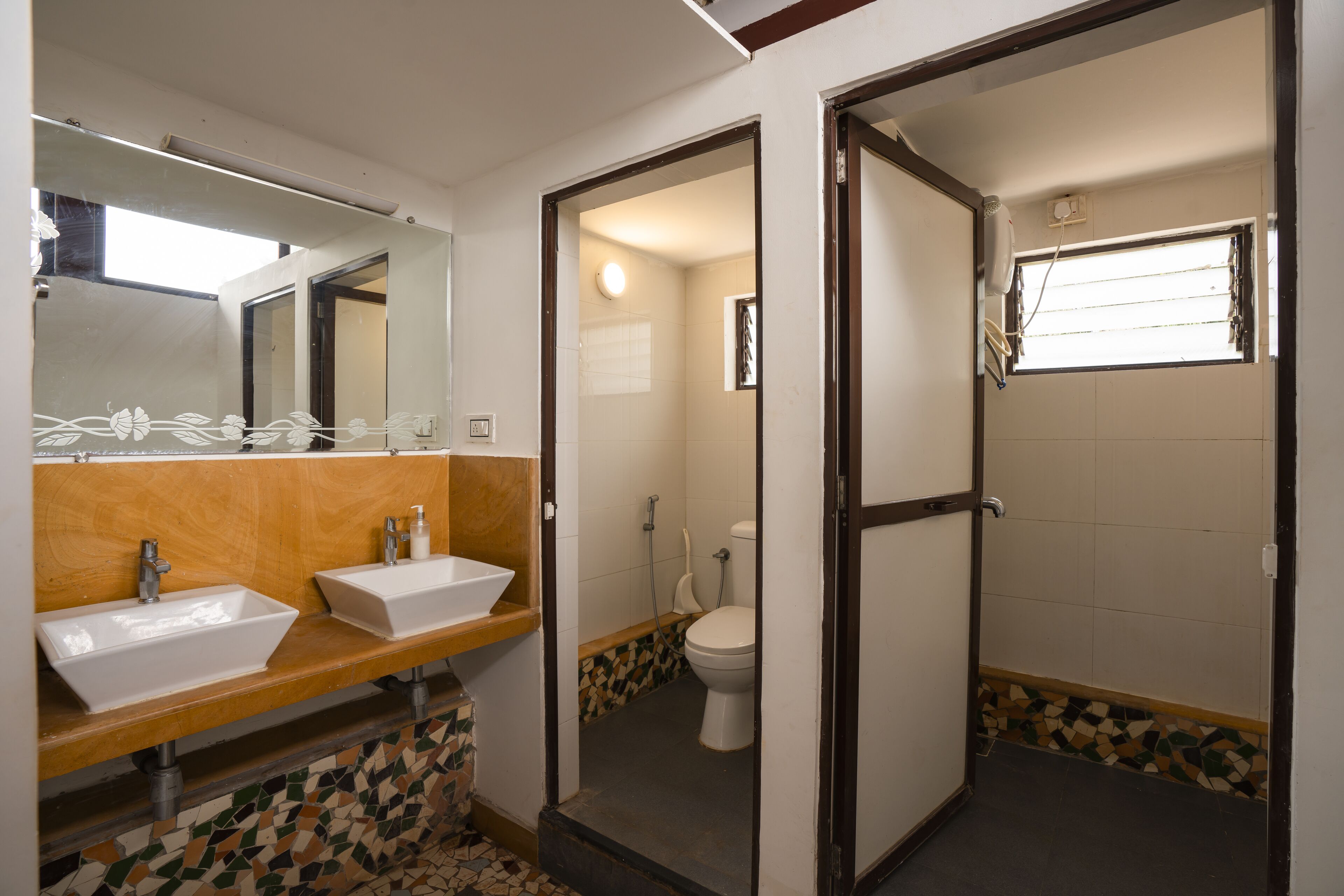 Un baño con dos lavamanos, un inodoro y una zona de ducha.