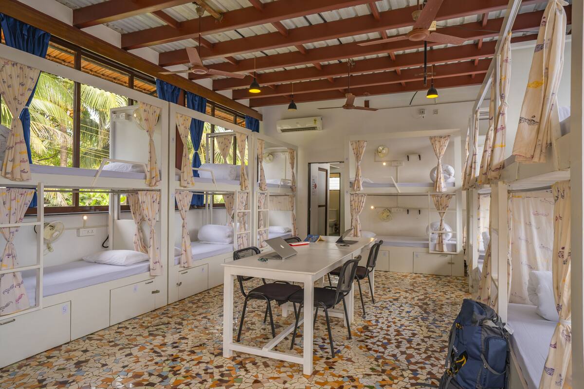 A room with bunk beds, a dining table, chairs, and a tiled floor.