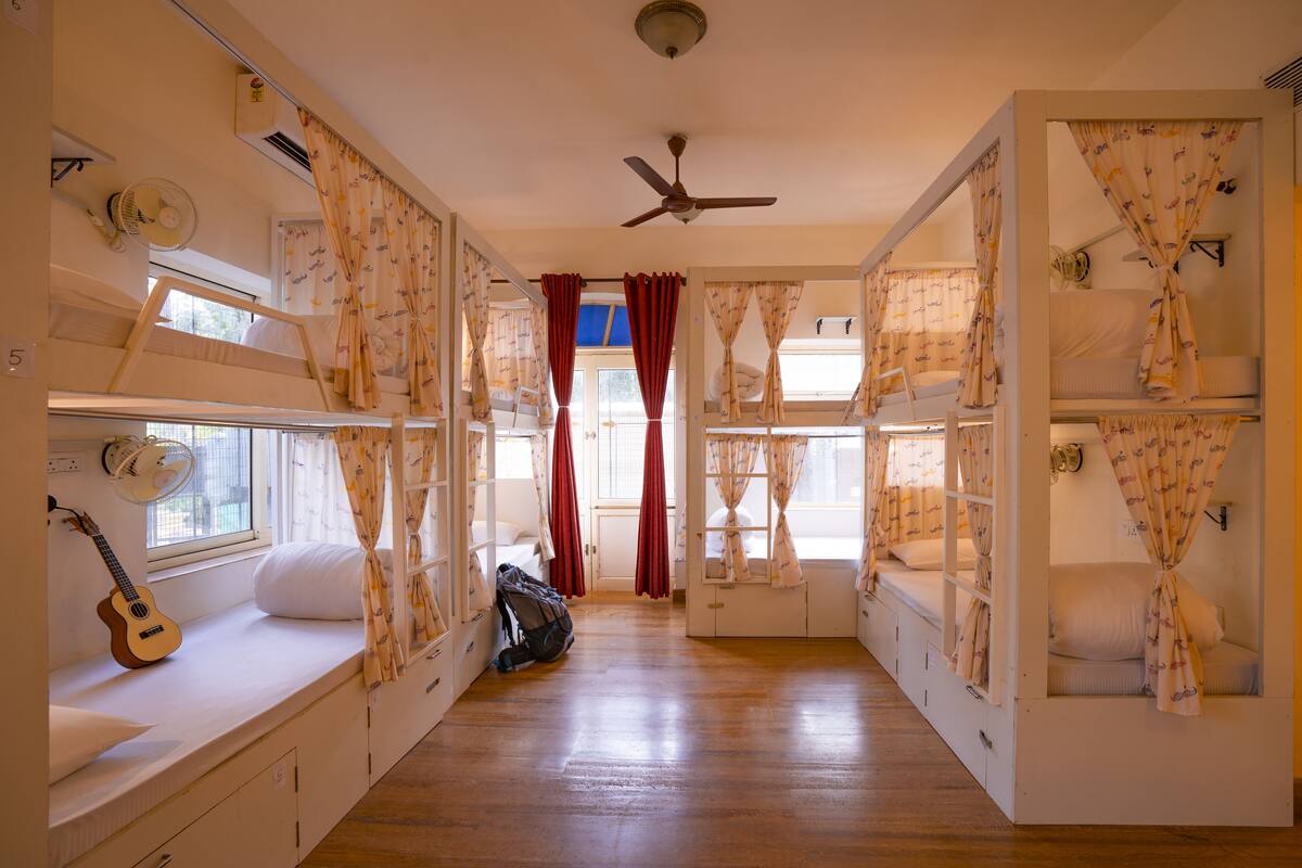 A room with bunk beds, a guitar, and a fan.