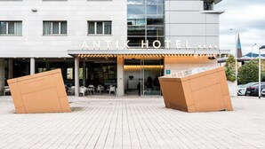 A modern hotel with a prominent glass facade, multiple balconies, and a central entrance with outdoor seating. - Hotel Antik San Sebastian (San Sebastián)