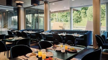 Un restaurante con mesas dispuestas para el desayuno, incluyendo platos de comida, bebidas y café.