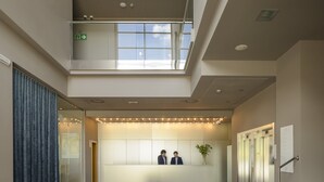 A modern hotel lobby with a reception desk, a staircase, and a large window. - Hotel Antik San Sebastian (San Sebastián)