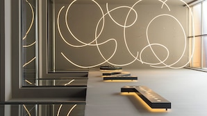 A modern interior with a minimalist design, featuring a long, sleek reception desk and a wall with abstract light patterns. - Hotel Antik San Sebastian (San Sebastián)