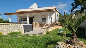 A two-story house with a stone wall, a covered patio, and outdoor furniture. - Natura Pura Wellness Oasis near Laghetti di Cavagrande (Avola)